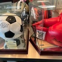 A soccer ball and boxing gloves are in display cases on a table.