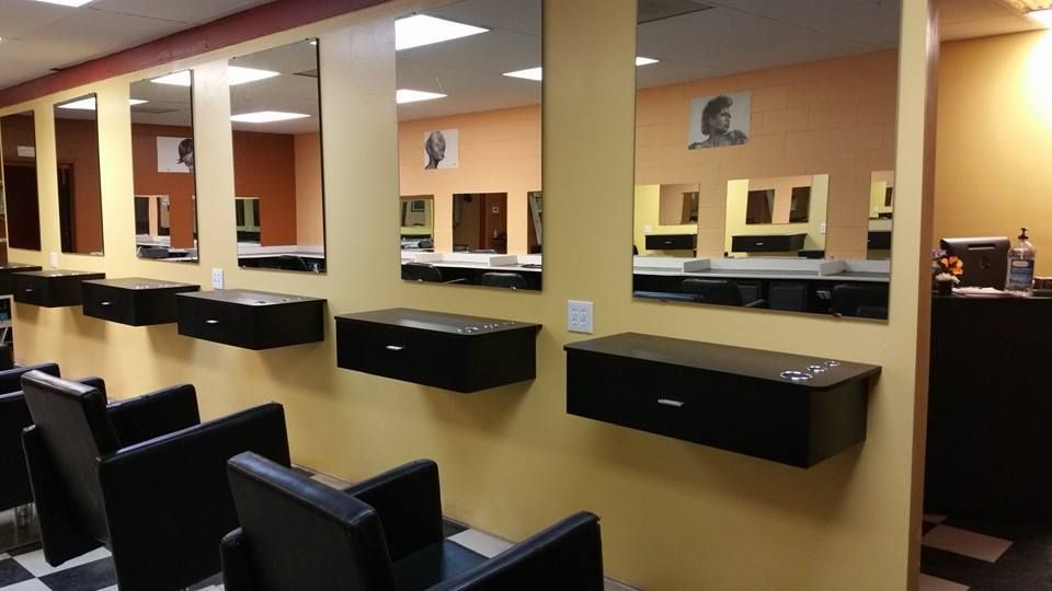 Salon interior with mirrors, stations, and black chairs against yellow walls.