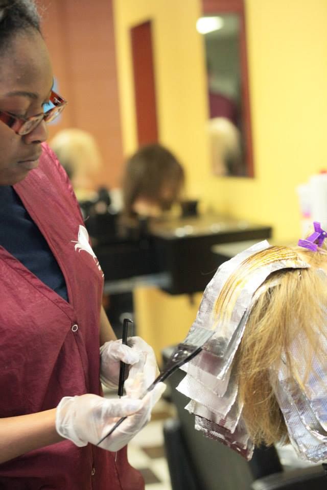 Hairdresser applying dye to blonde hair with foils in a salon.