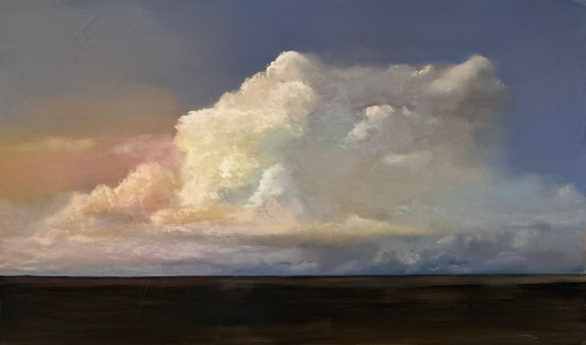 A large cloud in the sky with a rainbow in the background.