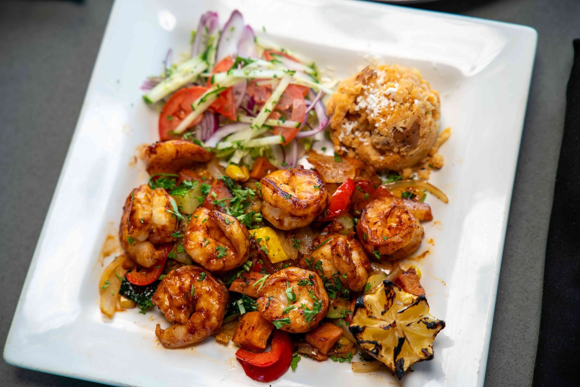 Grilled shrimp with vegetables, rice, and salad on a white plate.