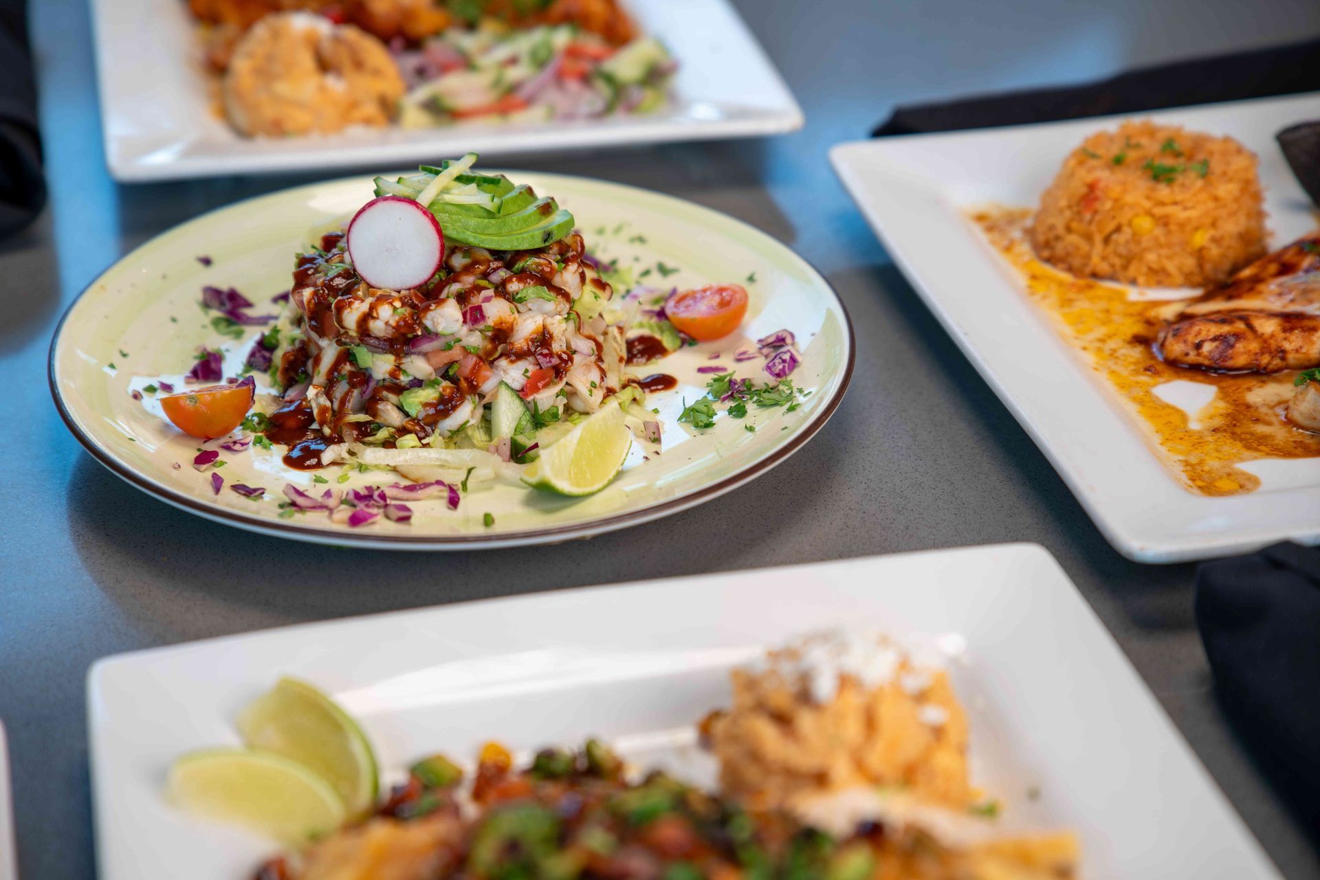 Plates of food, including ceviche, rice, and fish, sit on a table.