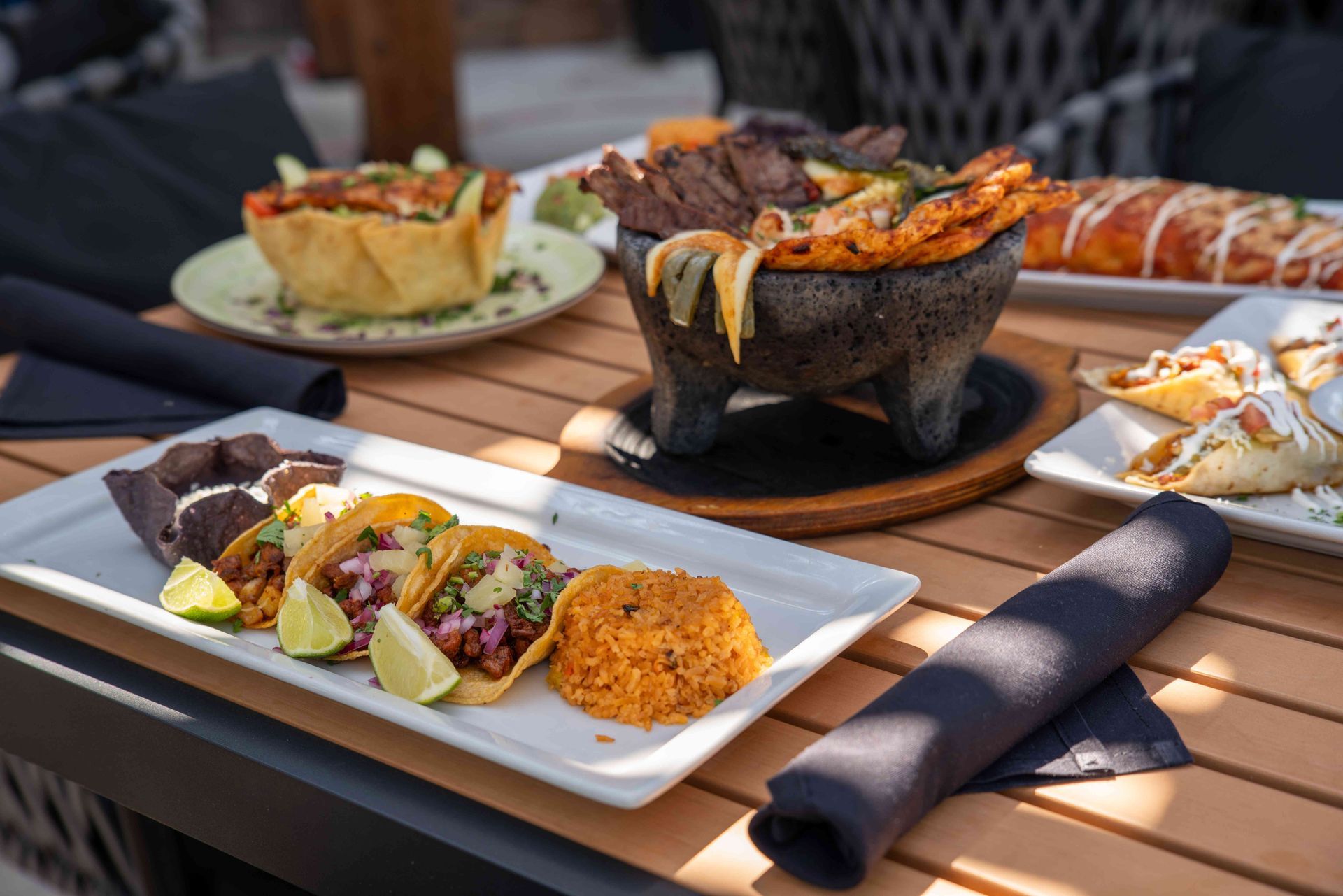 Mexican food spread on a table: tacos, rice, fajitas in a molcajete, and other dishes.