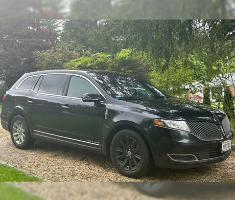 A black Lincoln Continental is parked on a gravel driveway