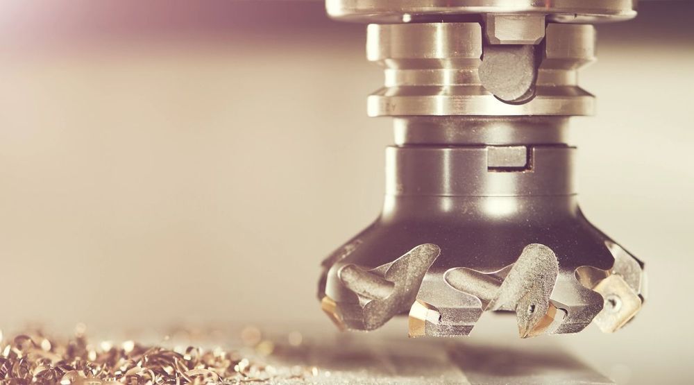 Close-up of a metal milling machine head carving away material, creating small shavings.
