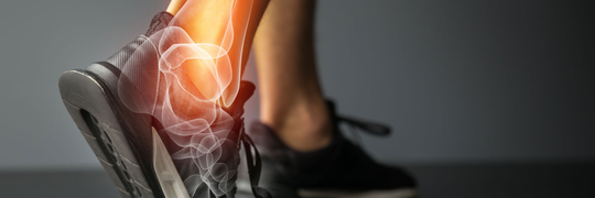 Foot in a black sneaker with a highlighted ankle, possibly indicating pain or injury.