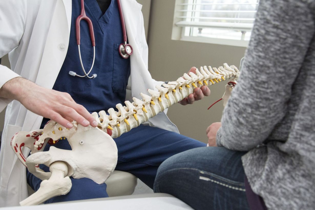Doctor showing a spine model to a patient in an office setting.