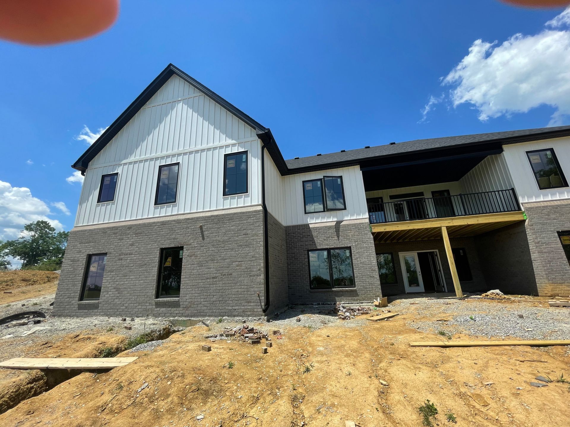 A large house is being built on top of a dirt hill.