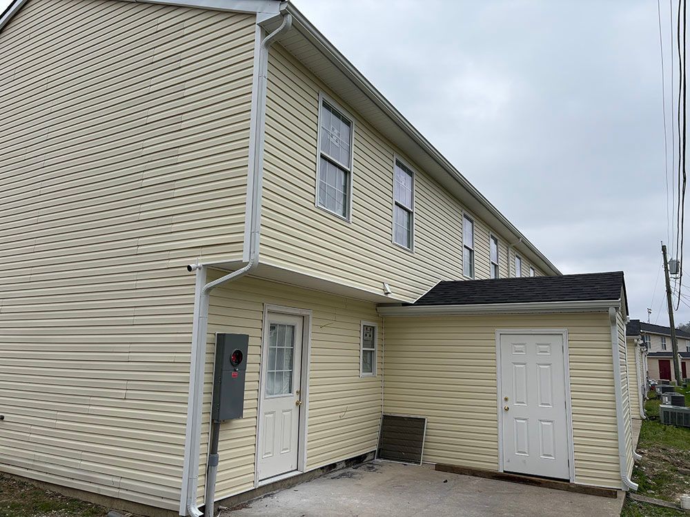 Beige two-story house exterior with white trim and an attached side entry porch.