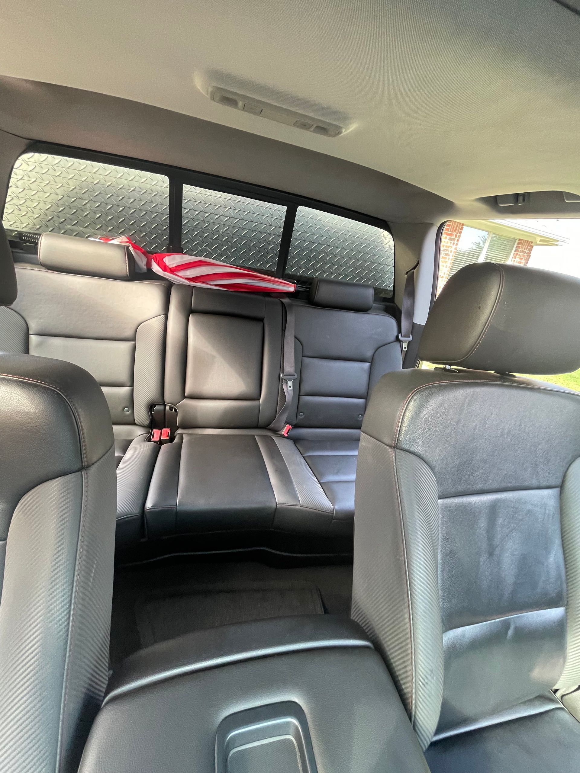 Interior of a black truck with leather seats. An American flag is visible through the back window.