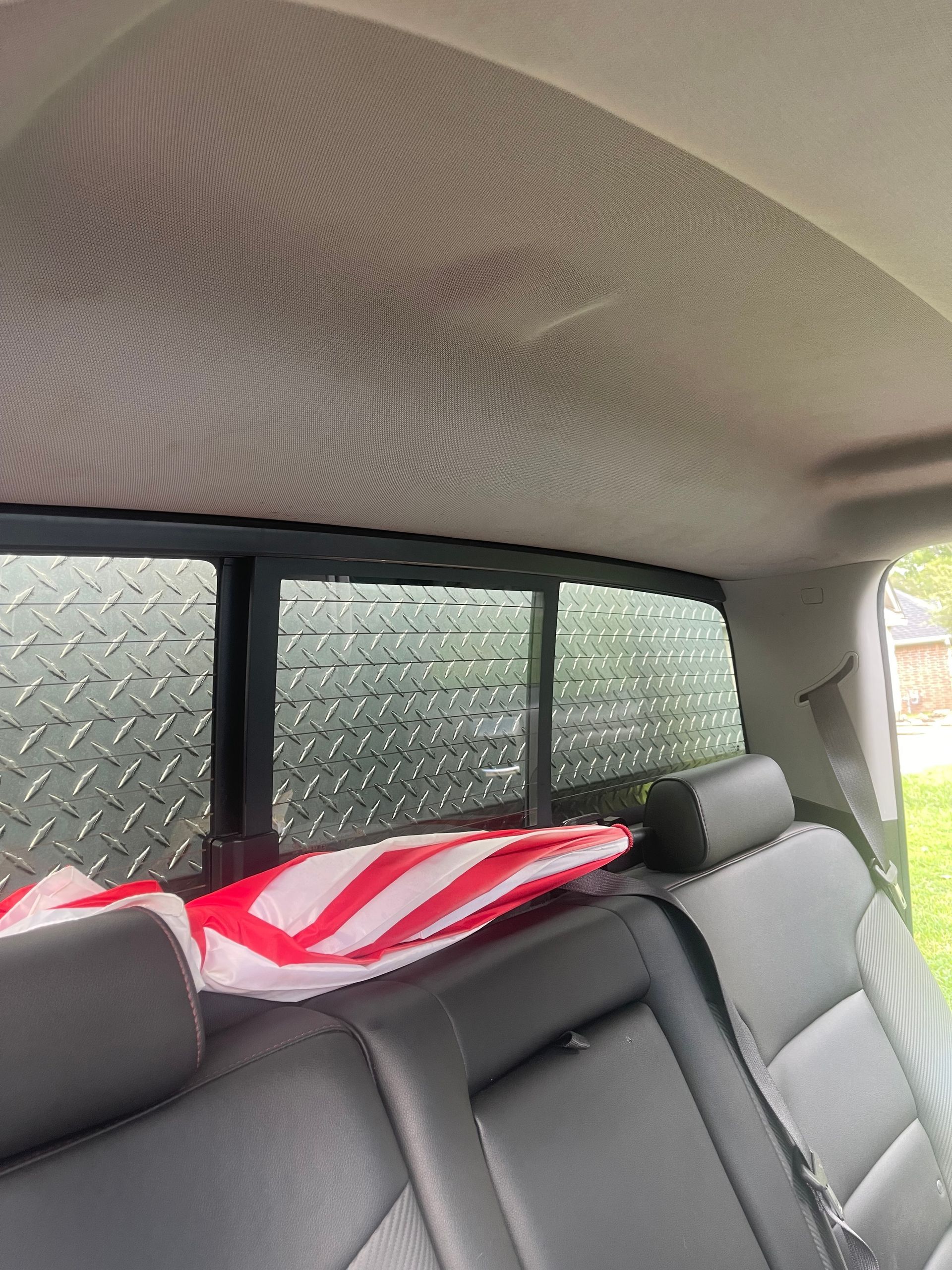 Back interior of a truck with a diamond-plated rear window and American flag on the rear seat.