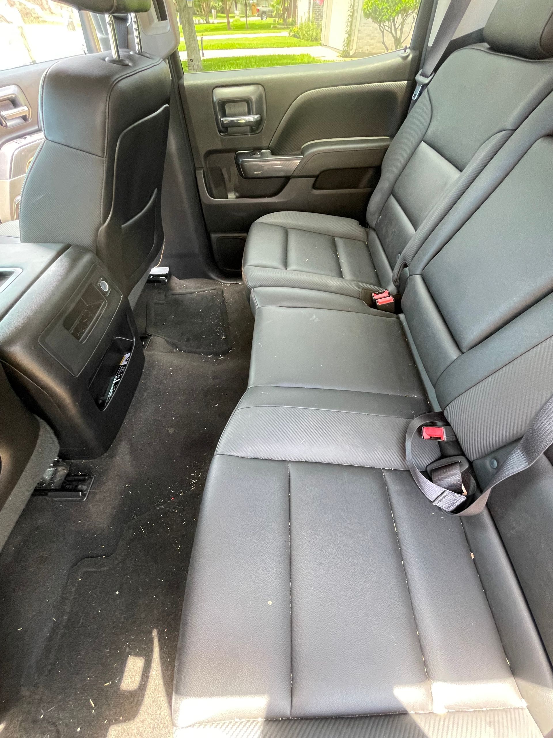 Black leather truck backseat; dirty black carpet.