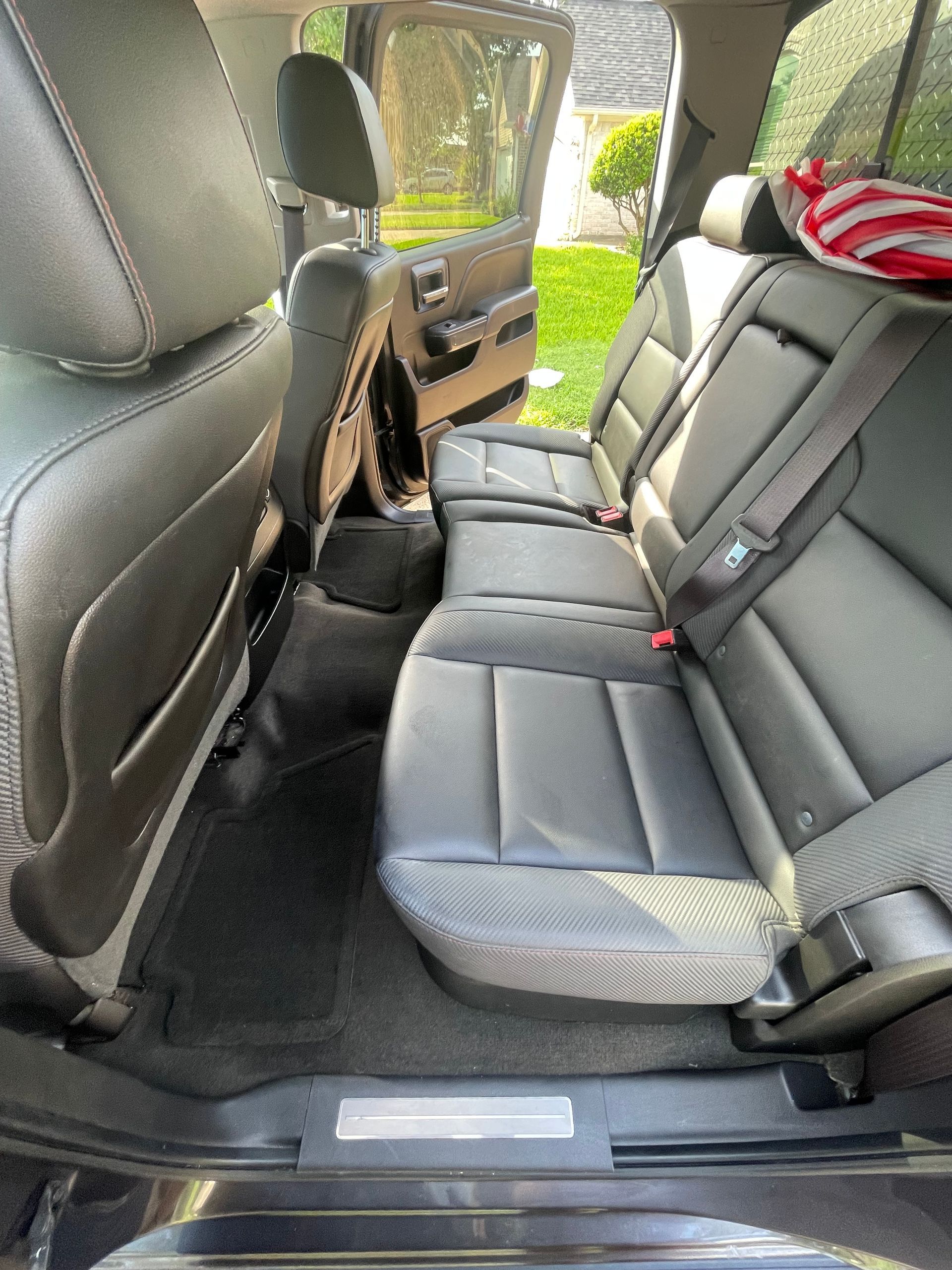 Black leather truck interior, showing rear seats, floor mats, and door opening.