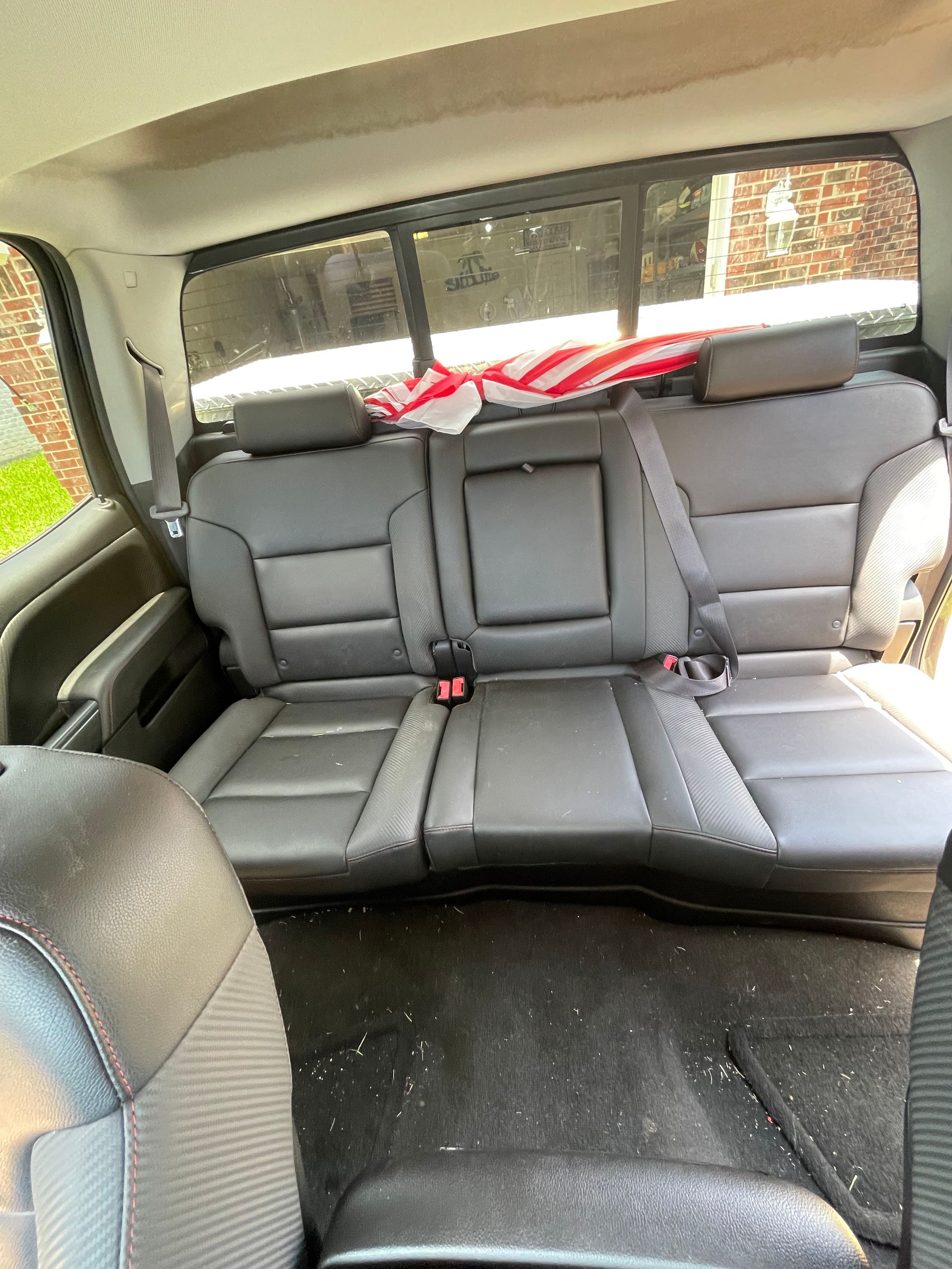 Back seats of a gray pickup truck with an American flag visible through the rear window.