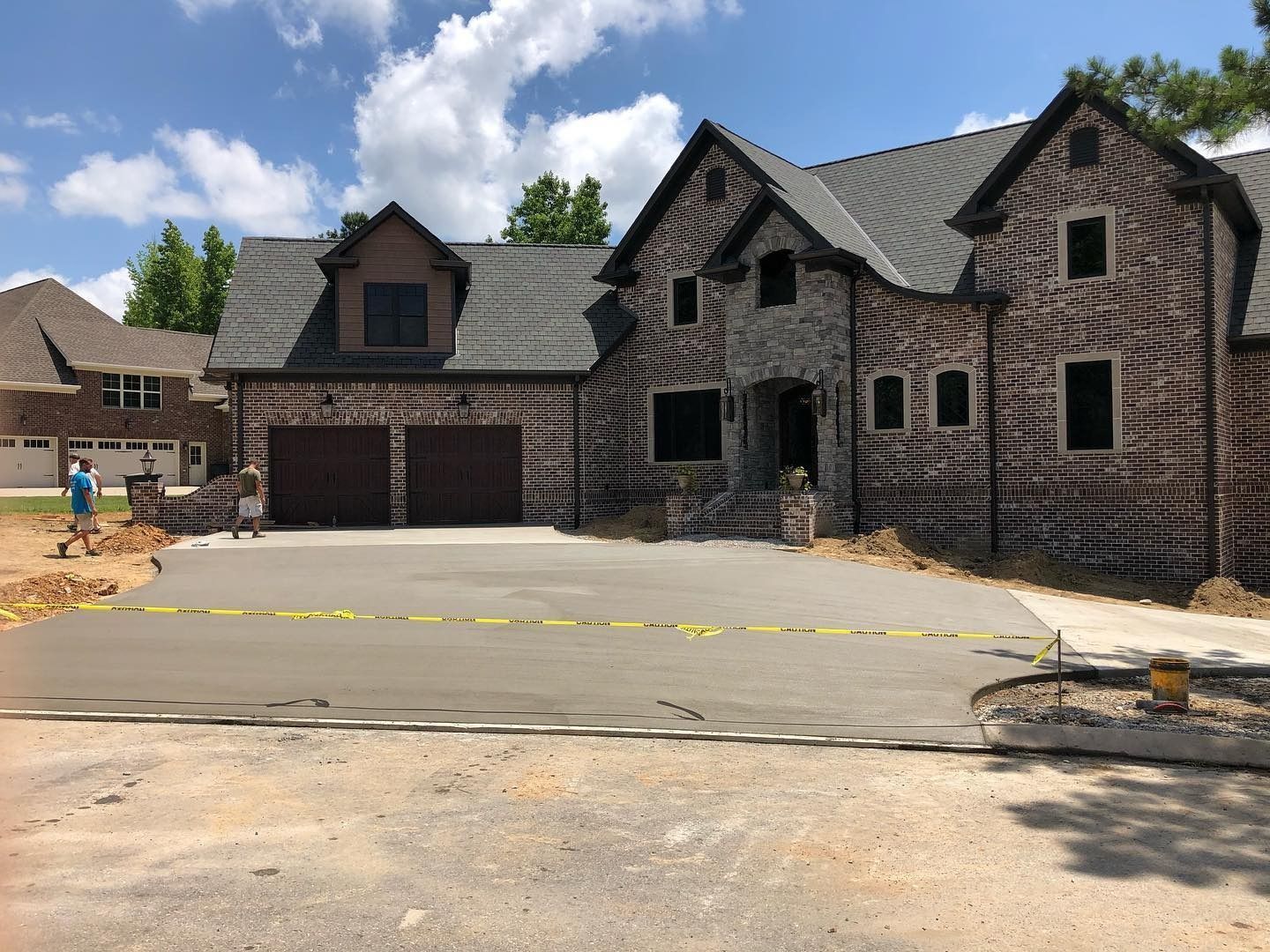 New brick home with gray driveway and caution tape.