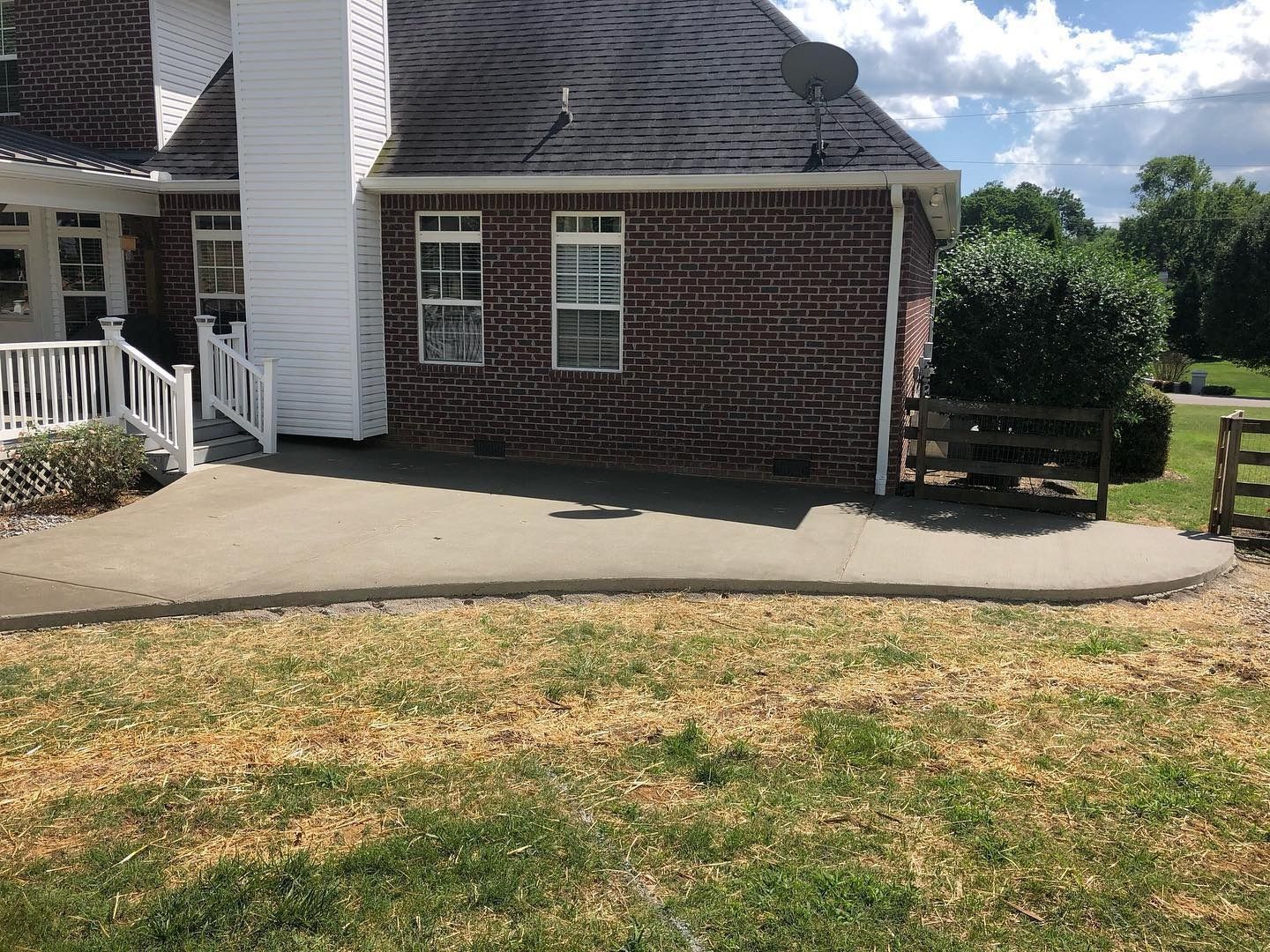 A brick house with a concrete patio and a grassy yard.