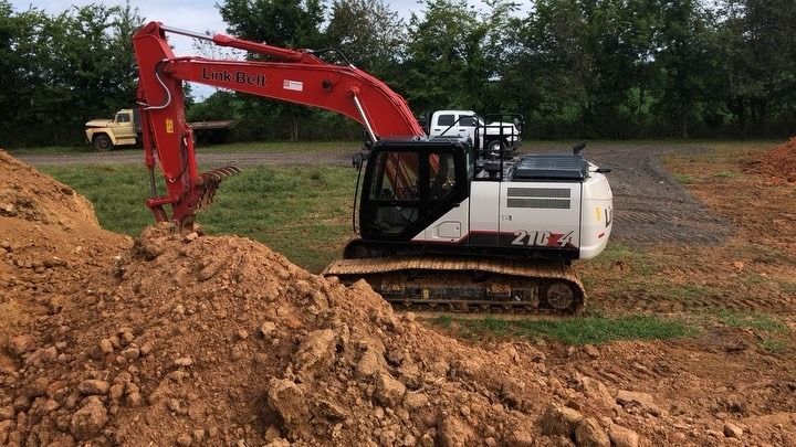Red and white excavator digging in a dirt pile, in a construction site.