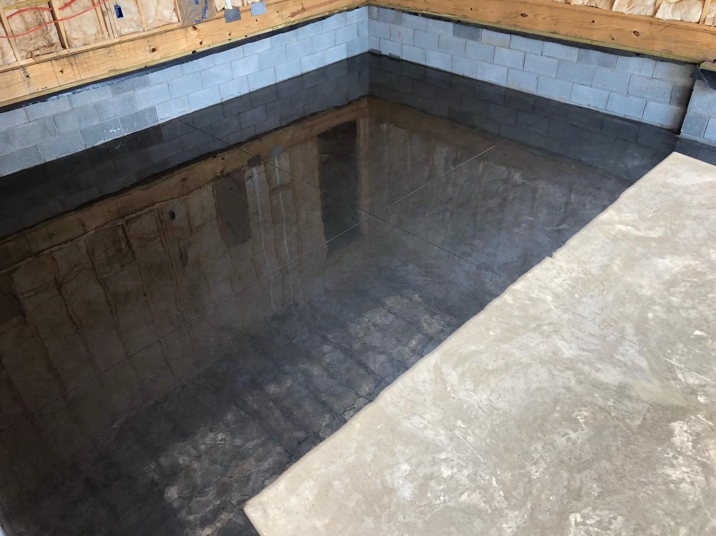 Concrete foundation walls and floor. Interior view with reflected light, likely after recent concrete pour.