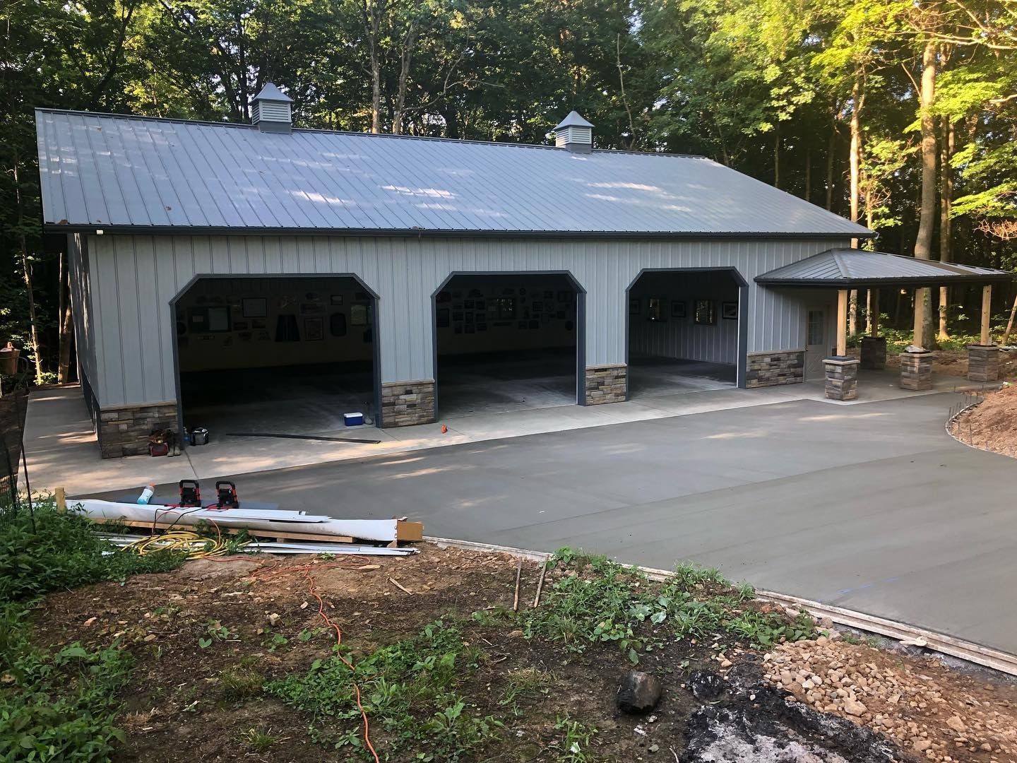 Gray garage with three bays and stone accents, concrete driveway, and a small porch.