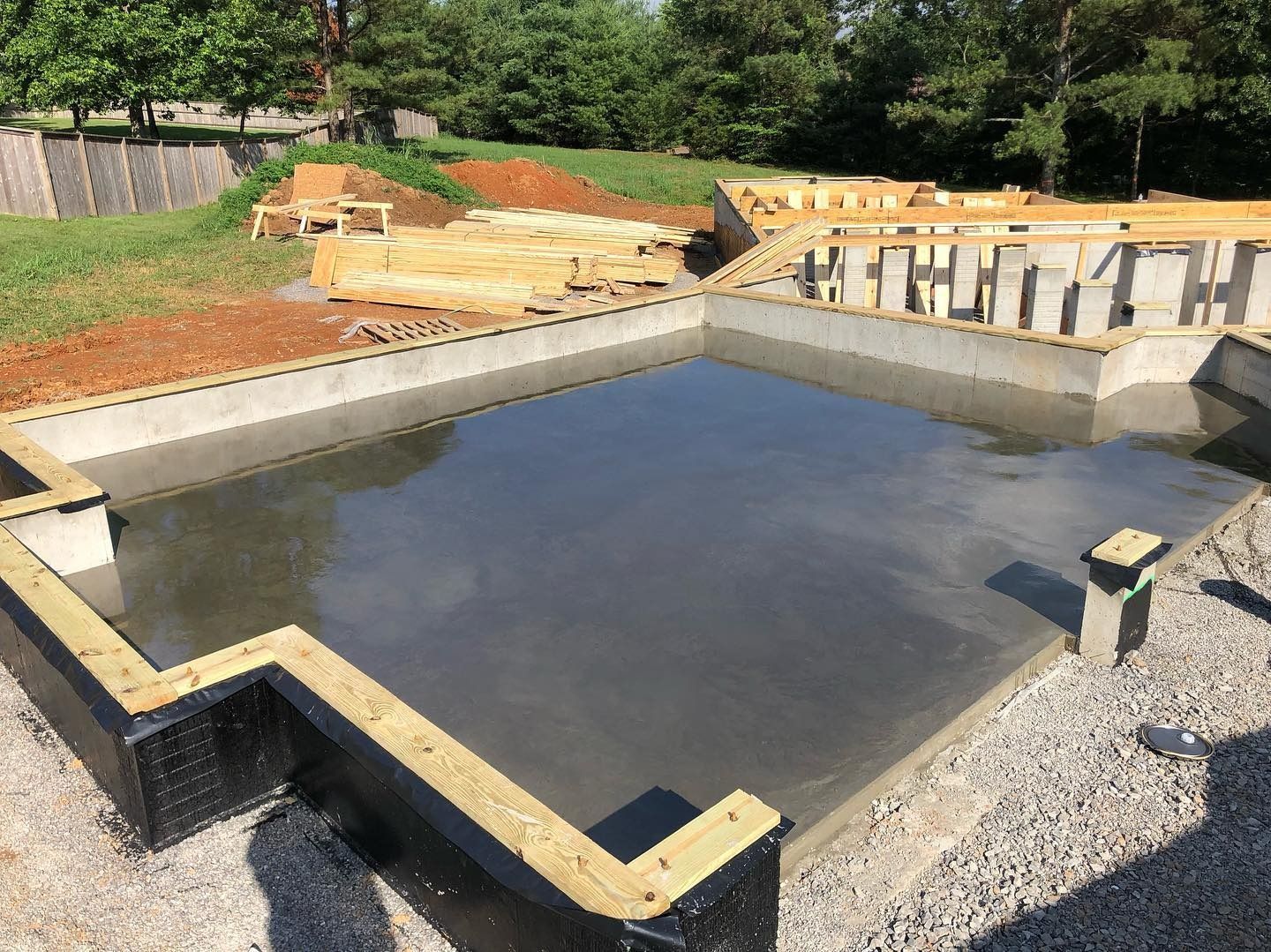 Construction site with a concrete foundation, wooden frame, and gravel.