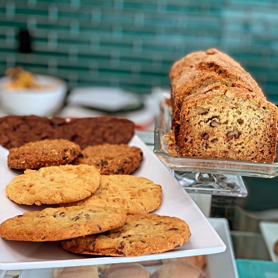 A plate of cookies and a loaf of banana bread on a table.