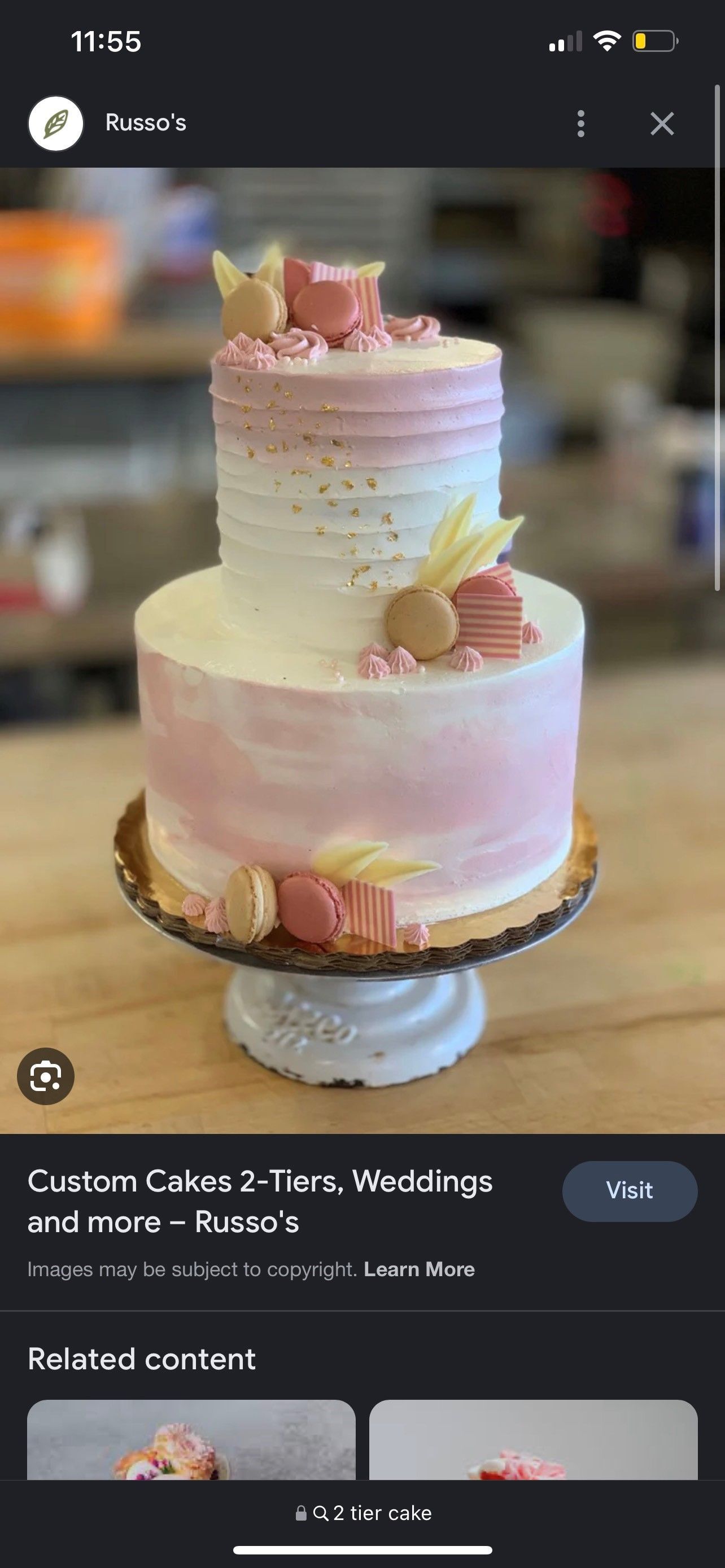 A pink and white cake is sitting on top of a wooden table.