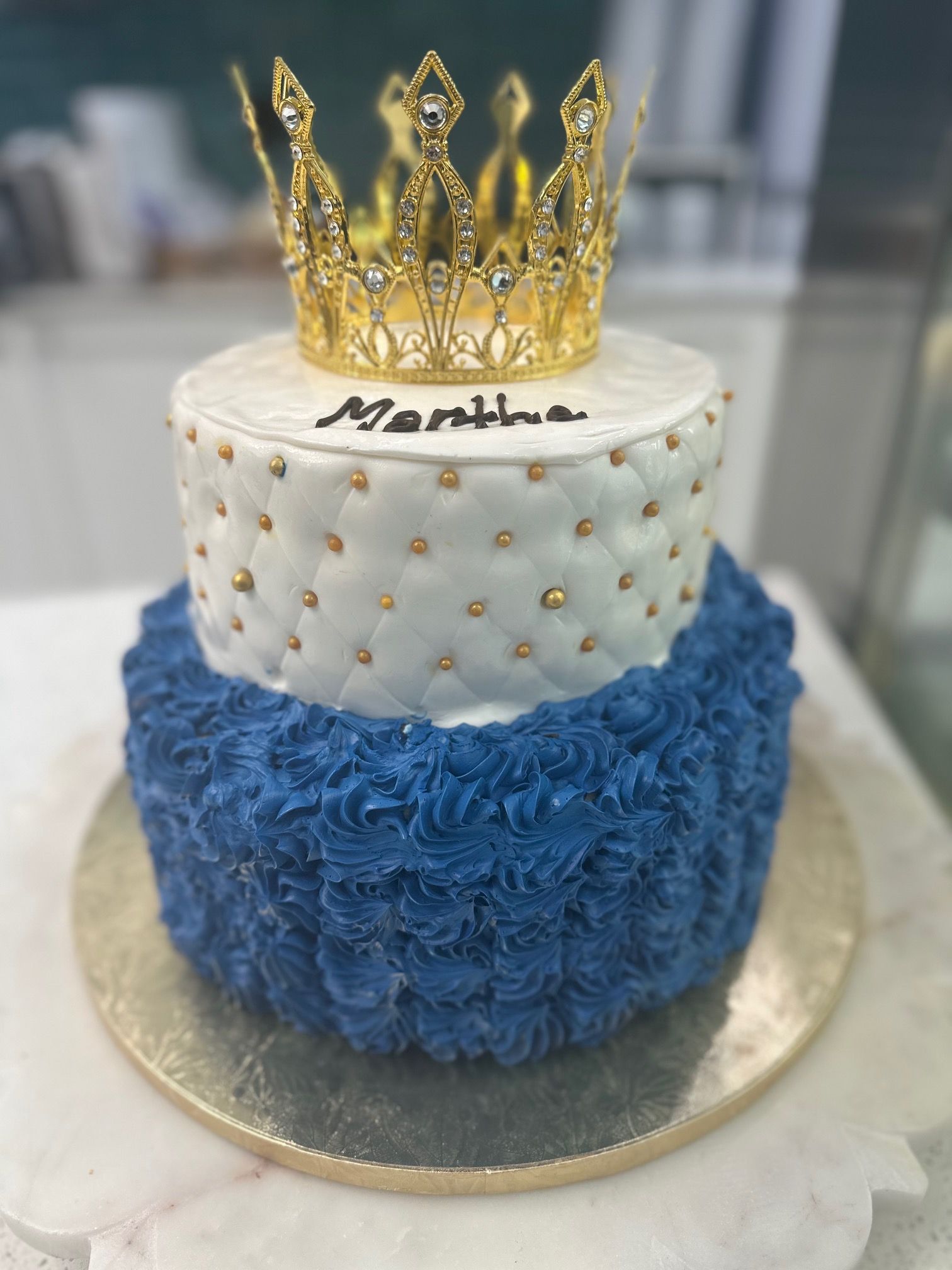 A blue and white cake with a gold crown on top.