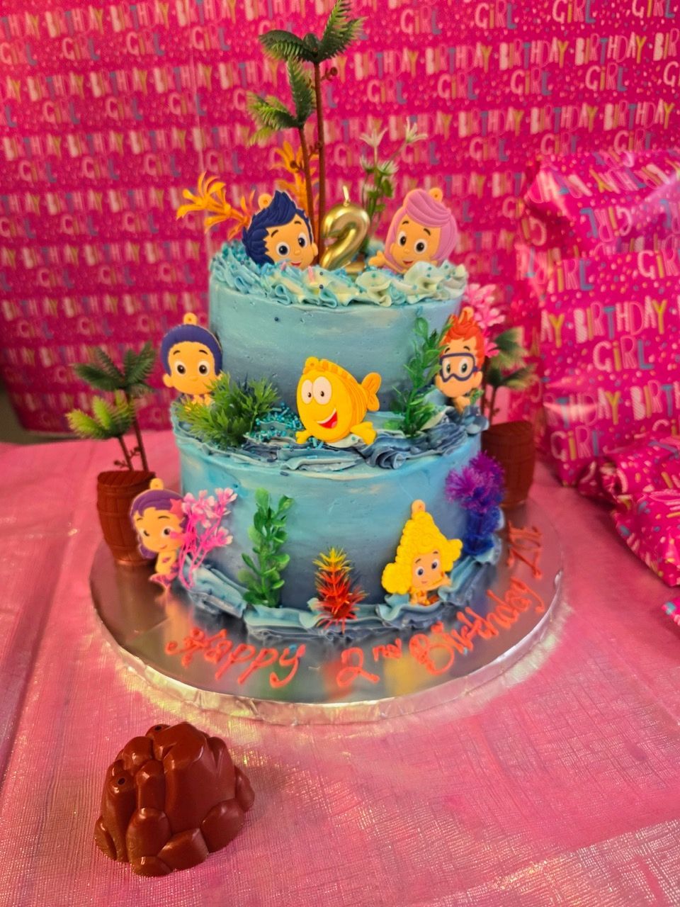 A birthday cake with bubble guppies on it is on a table.