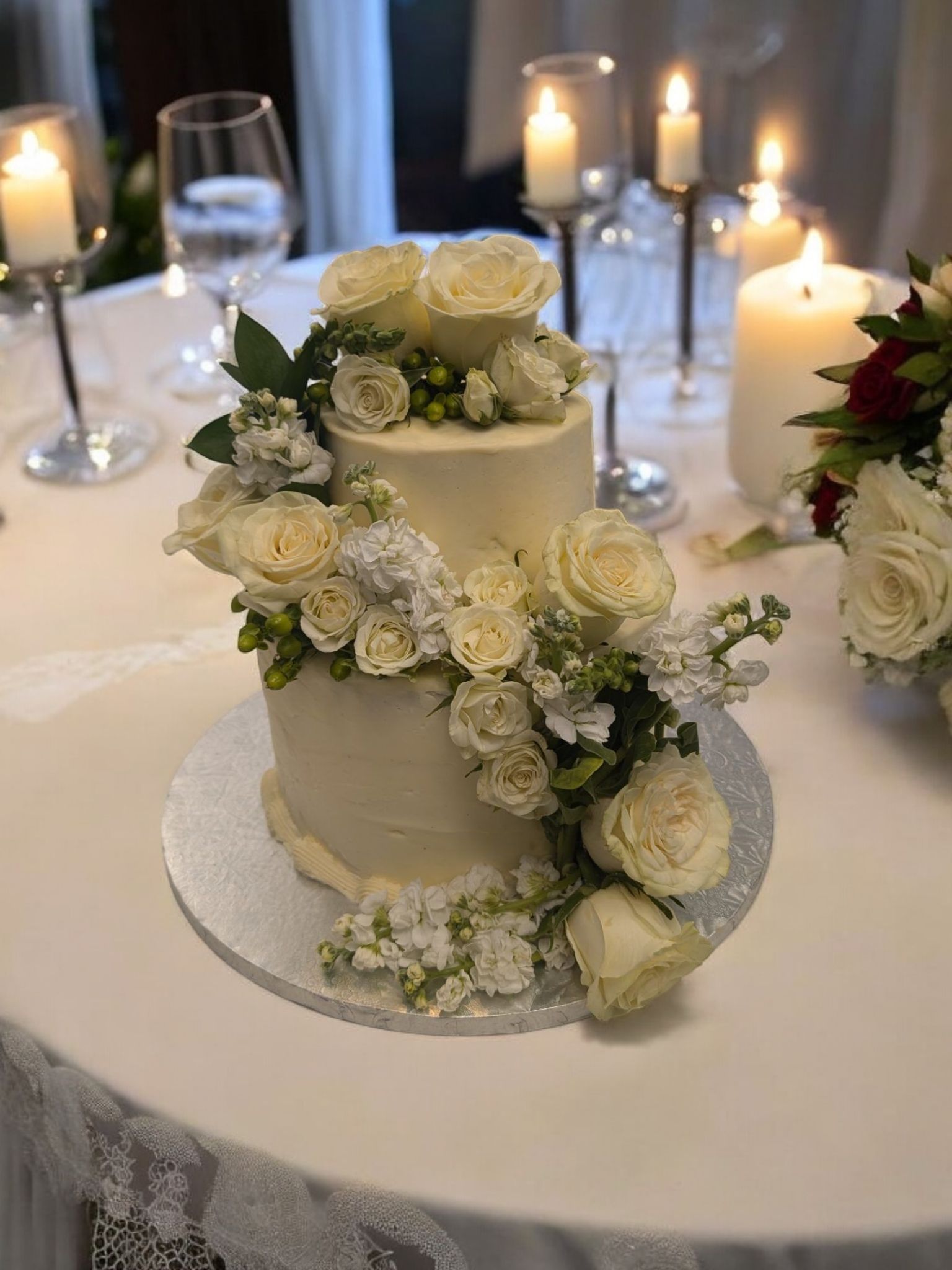 A wedding cake is sitting on a table with candles and flowers.