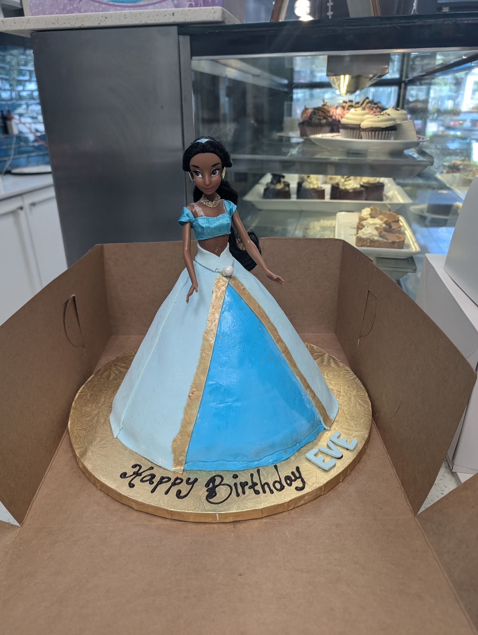 A birthday cake in the shape of a doll in a blue dress