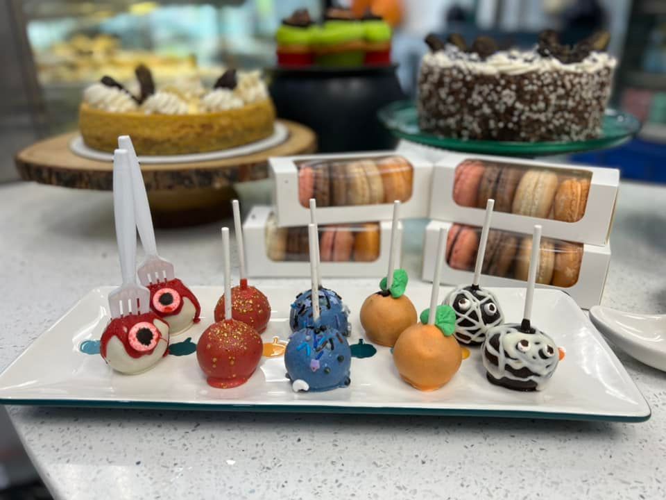 A white plate topped with a variety of cake pops and macarons.