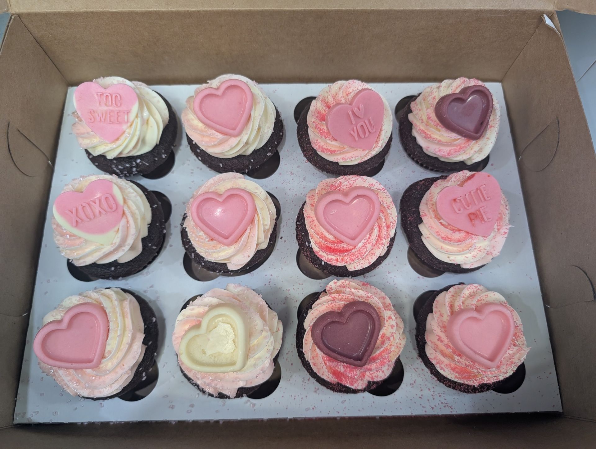 A box of cupcakes with hearts on them that say i love you