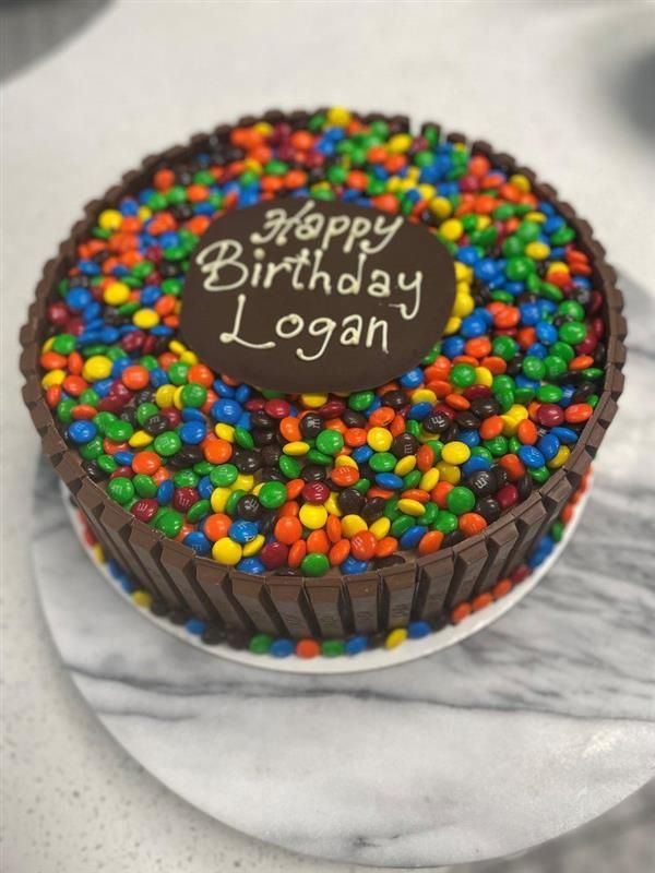 A birthday cake that says happy birthday logan on it