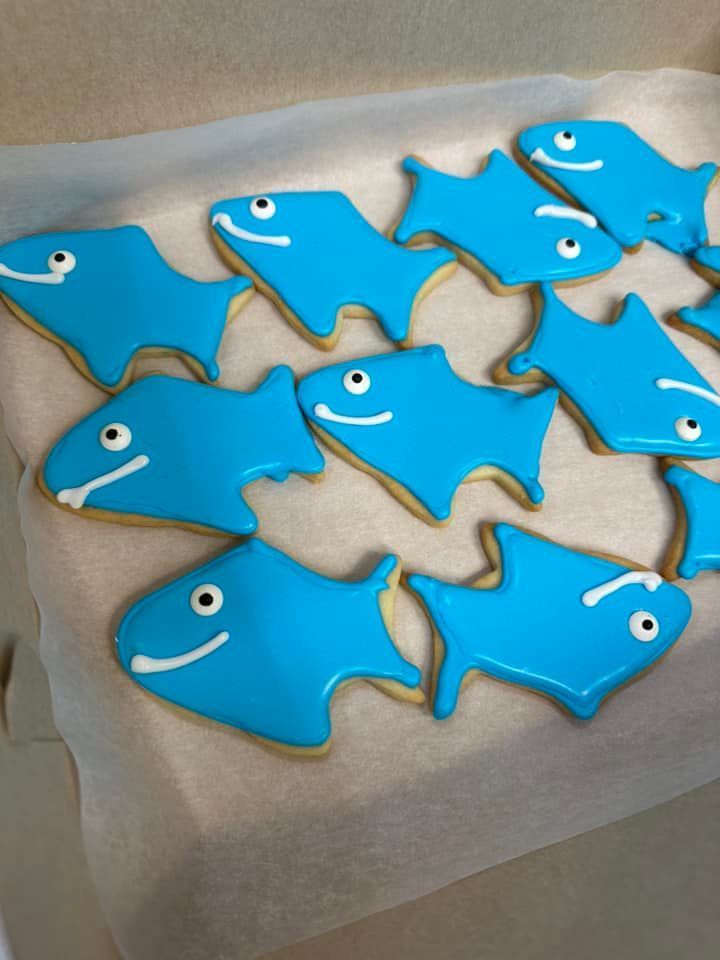 A box of blue fish shaped cookies with smiley faces on them