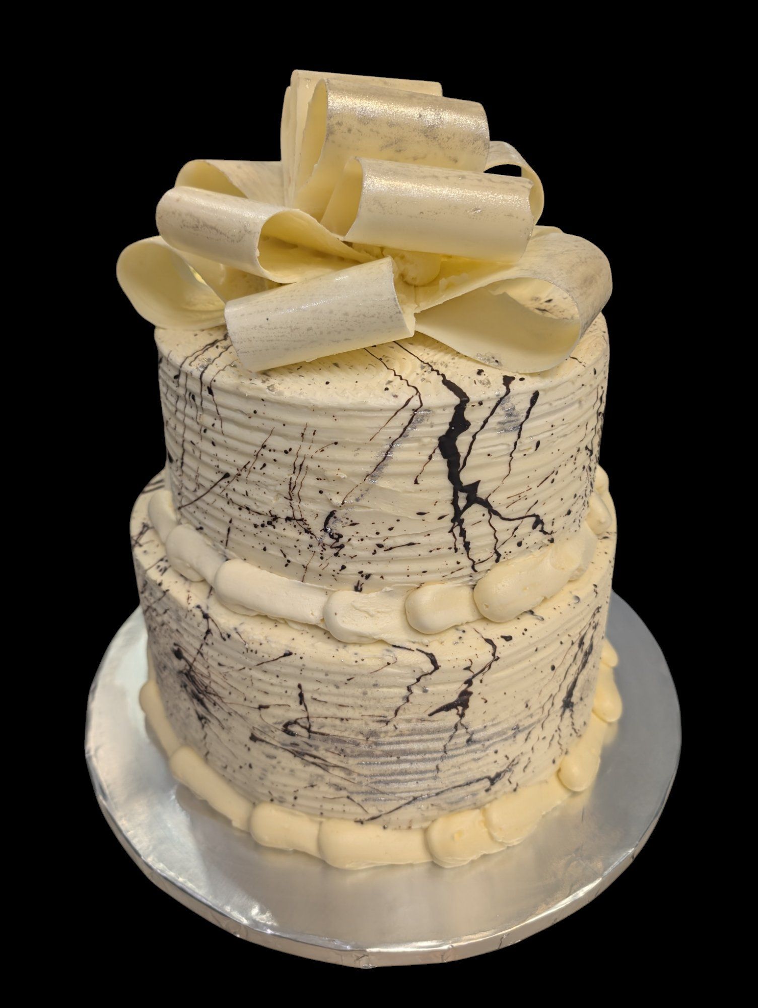 A white and black cake with a bow on top of it.