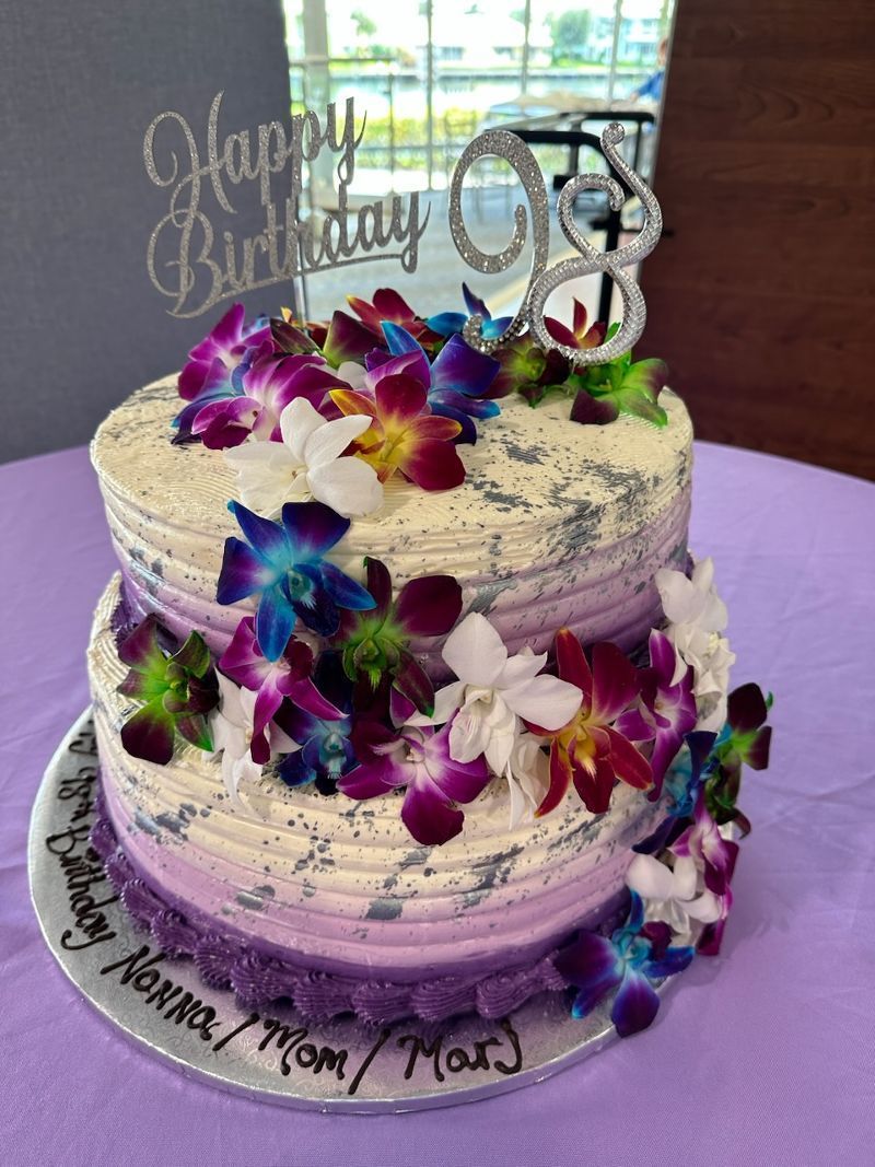 A purple and white birthday cake with flowers on it