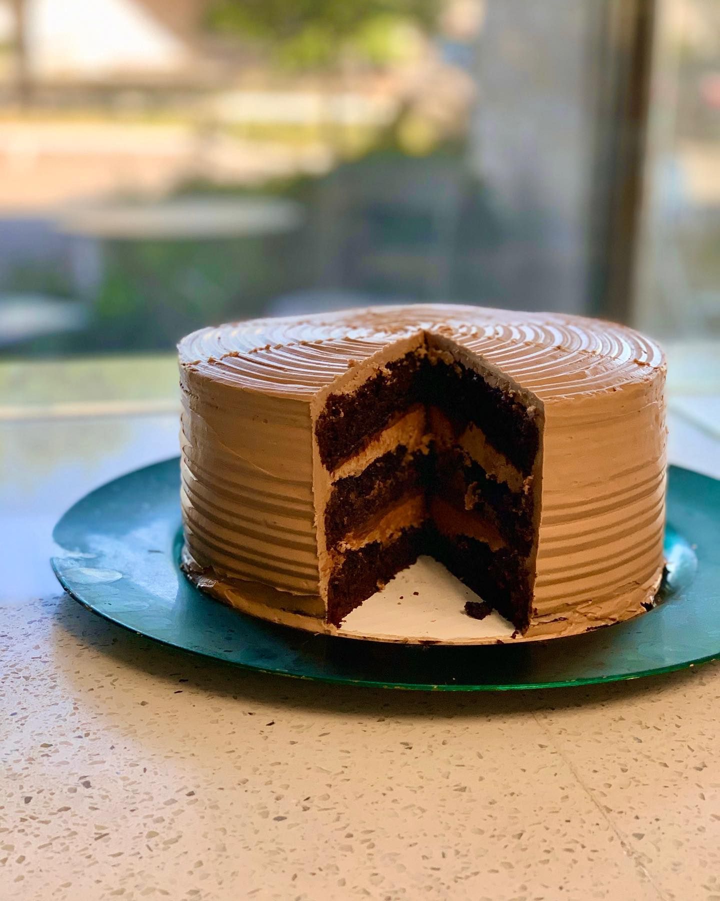 A chocolate cake with a slice taken out of it is on a plate.