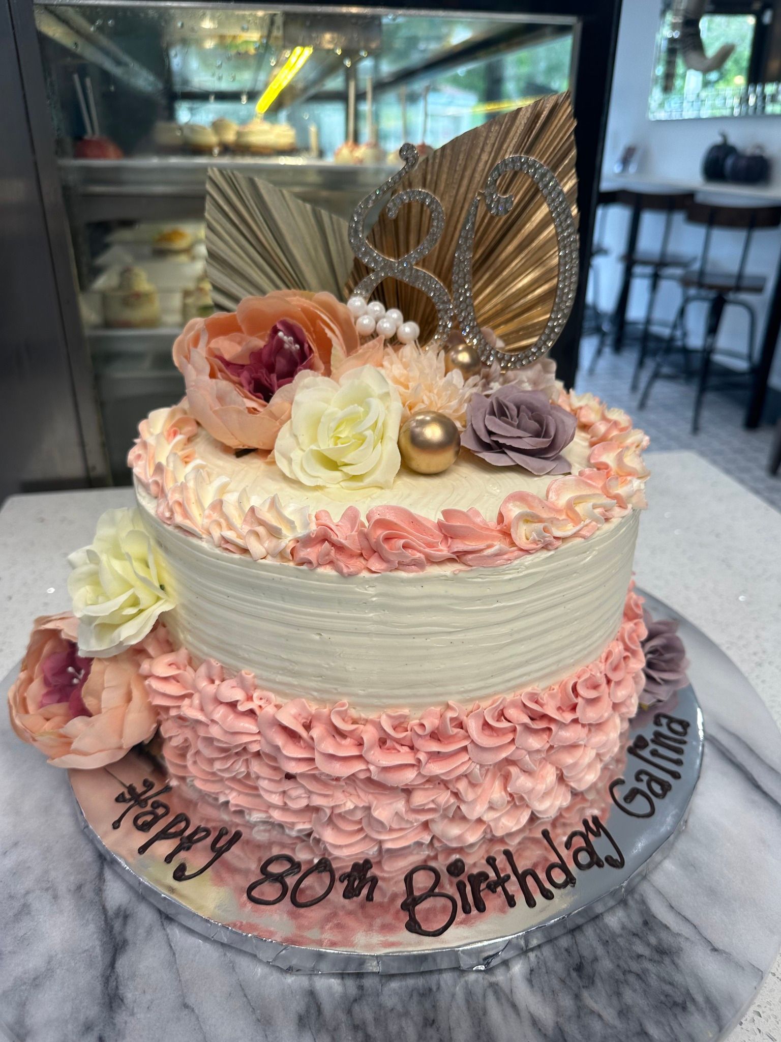 A birthday cake with flowers and a crown on top is sitting on a table.