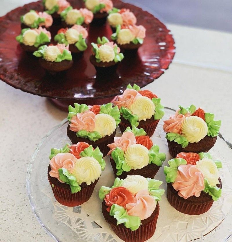 A plate of cupcakes decorated with pink and yellow frosting