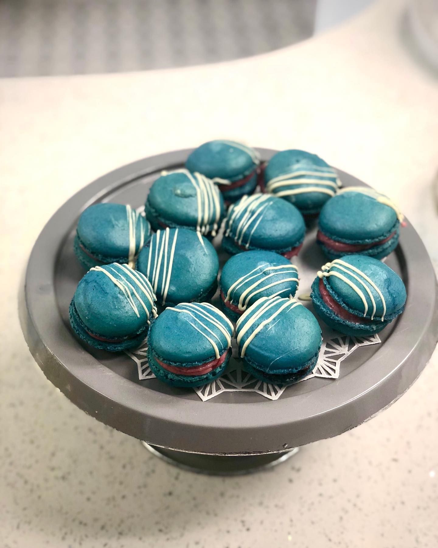 A bowl filled with blue macarons on a table.