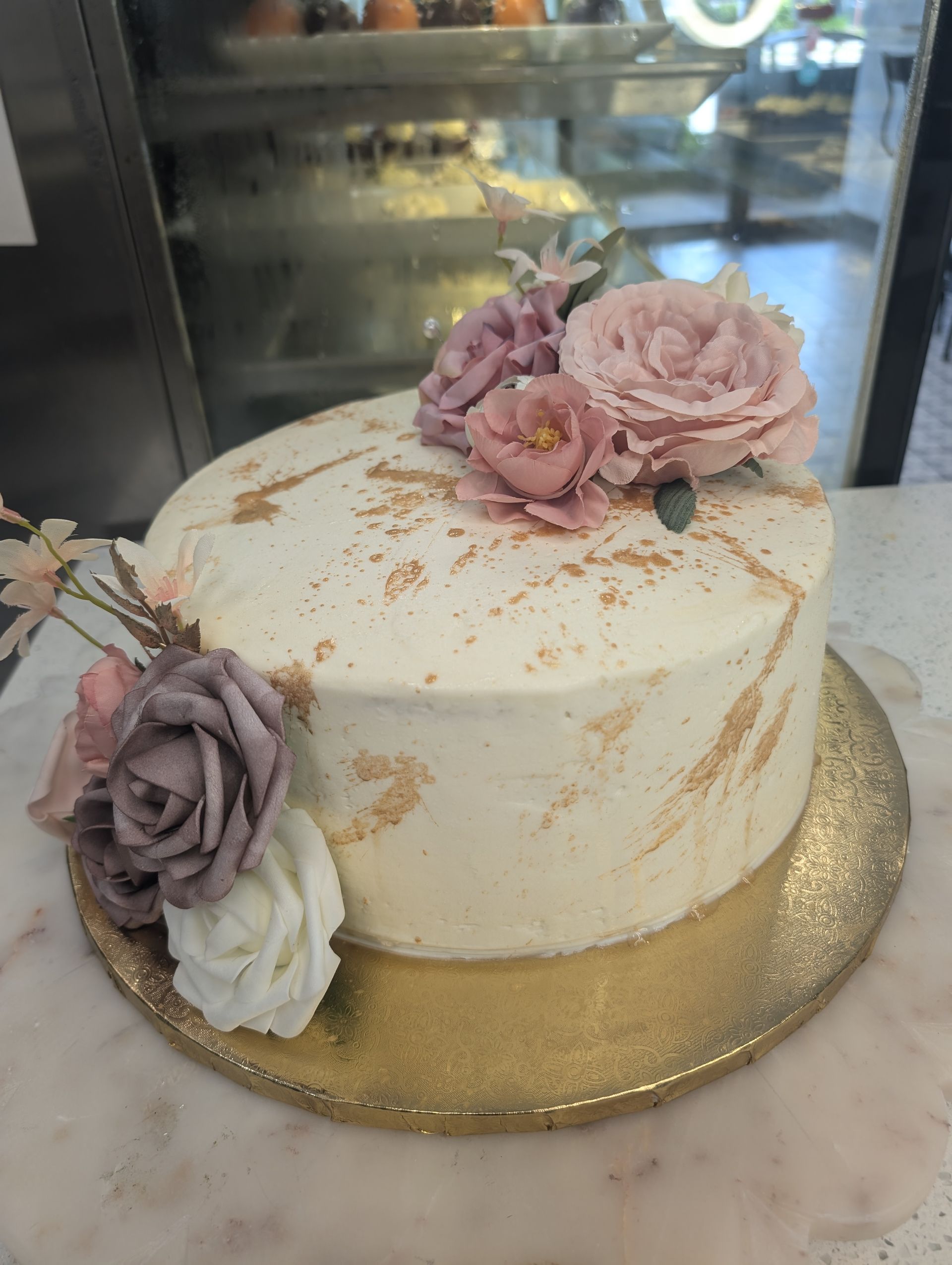 A white cake with pink and purple flowers on top is sitting on a table.