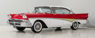 Classic red-and-white 1950s car in a studio setting, side view