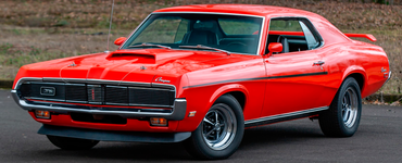 Red classic Cougar muscle car driving on a road, side view