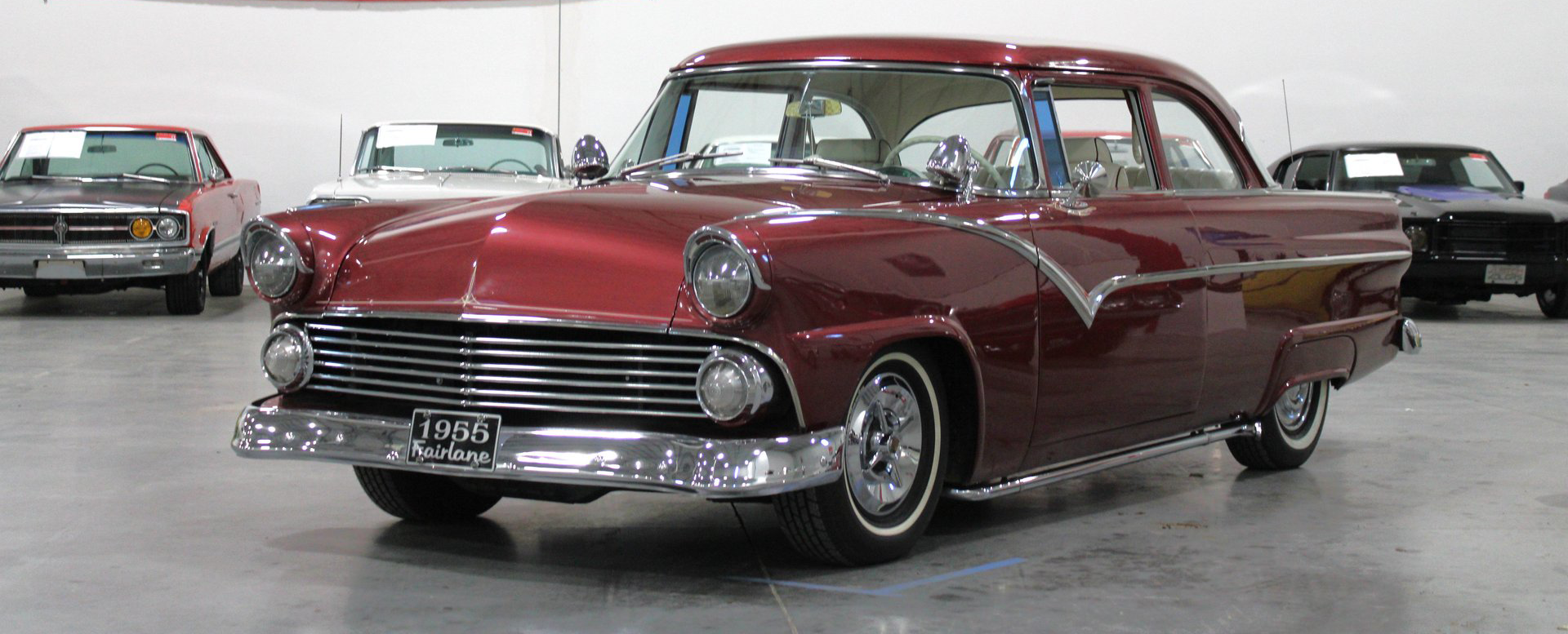 Maroon classic car with chrome details in an indoor showroom, front three-quarter view