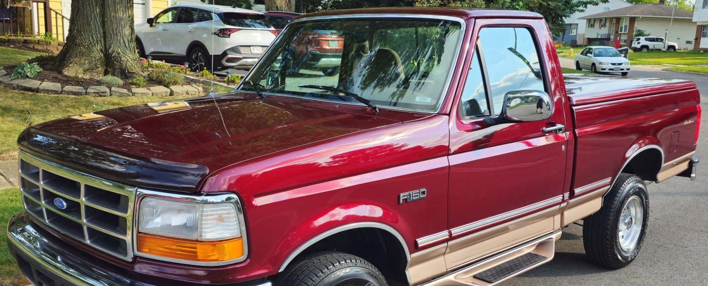 Red Ford F-150 pickup truck parked outdoors, shown from the front-left side.