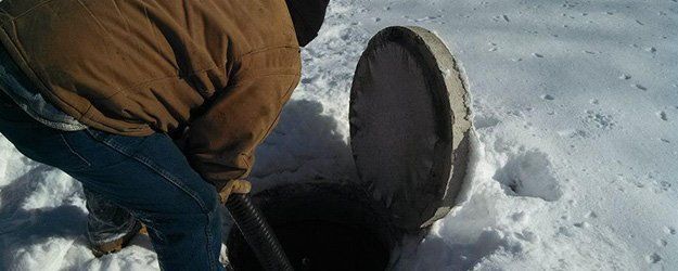 man cleaning septic tank in a snow covered ground
