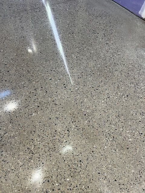 Polished concrete floor with a speckled appearance, reflecting light in a room.