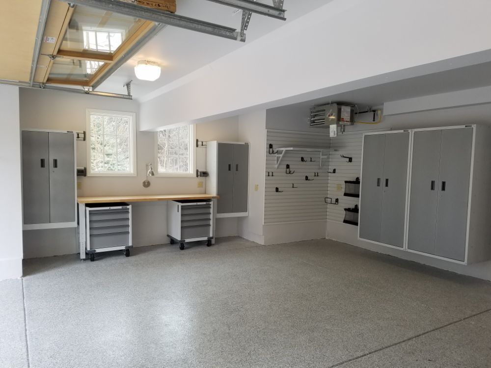 Spacious, well-lit garage with gray cabinets, work bench, and speckled floor.