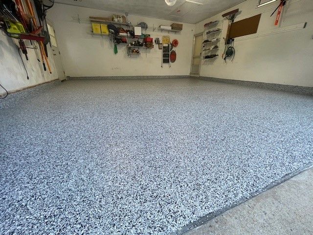 Garage with gray speckled epoxy floor, tools organized on walls.