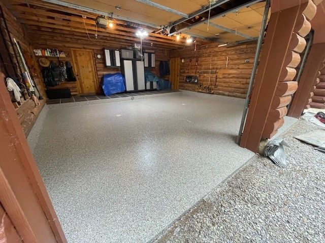 Garage with a speckled epoxy floor, wooden walls, and some storage.